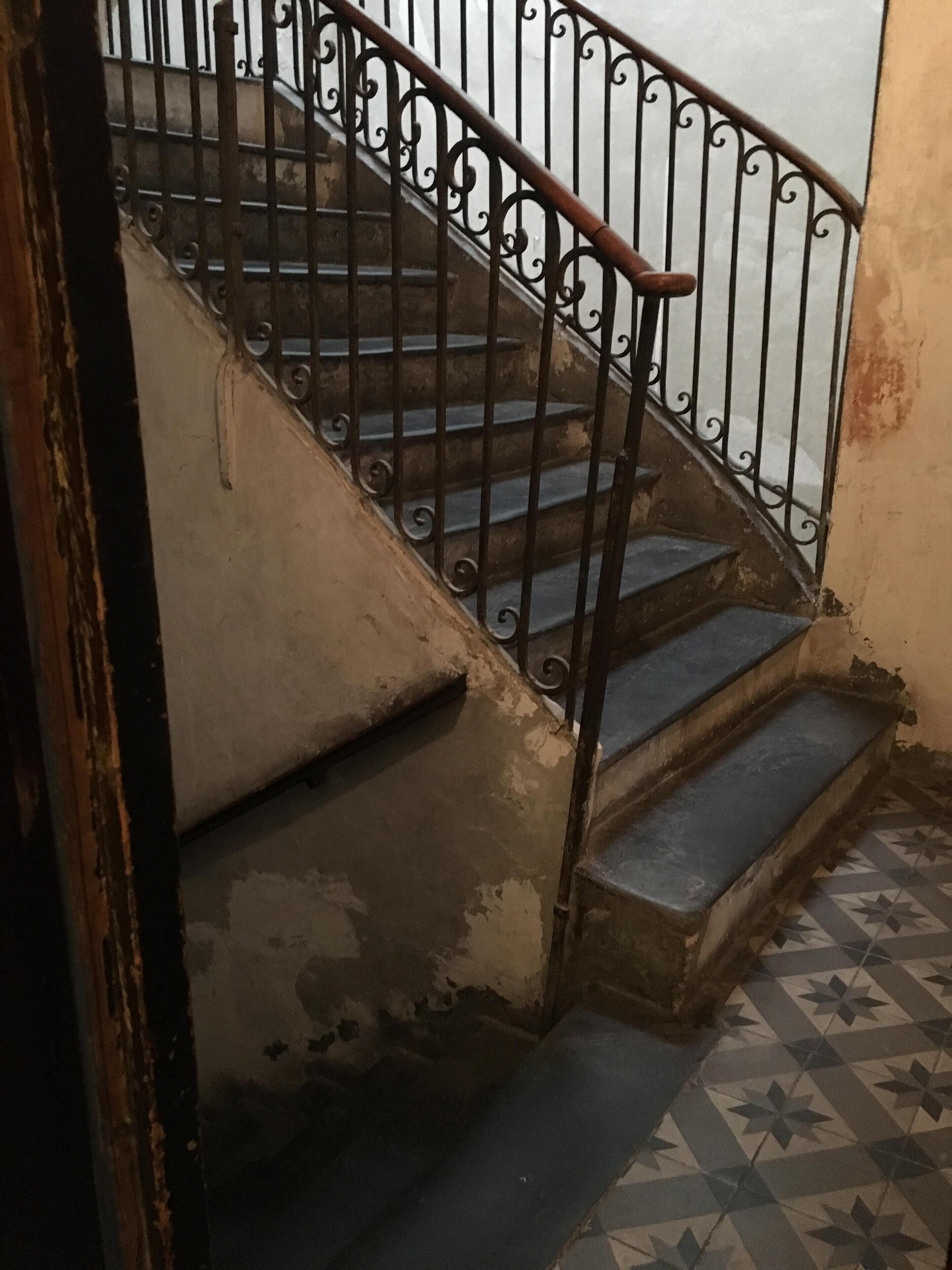 A staircase with a metal railing and worn steps.