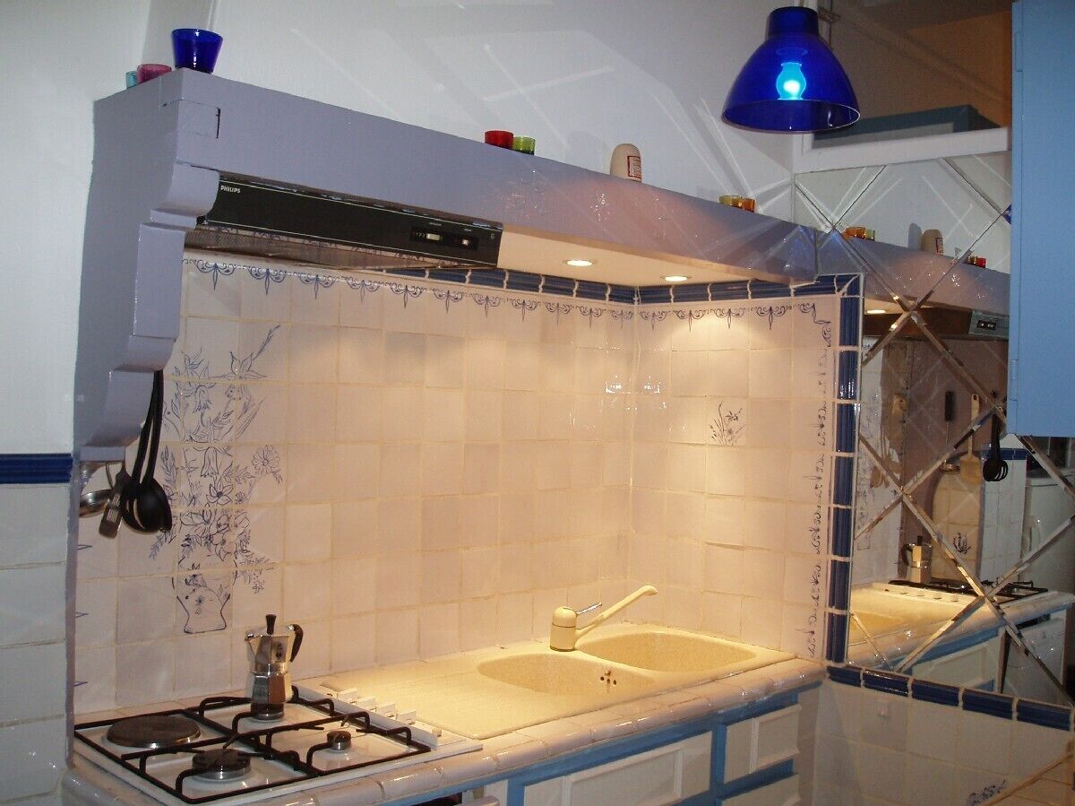Een keuken met een gasfornuis, een spoelbak en een blauwe hanglamp.