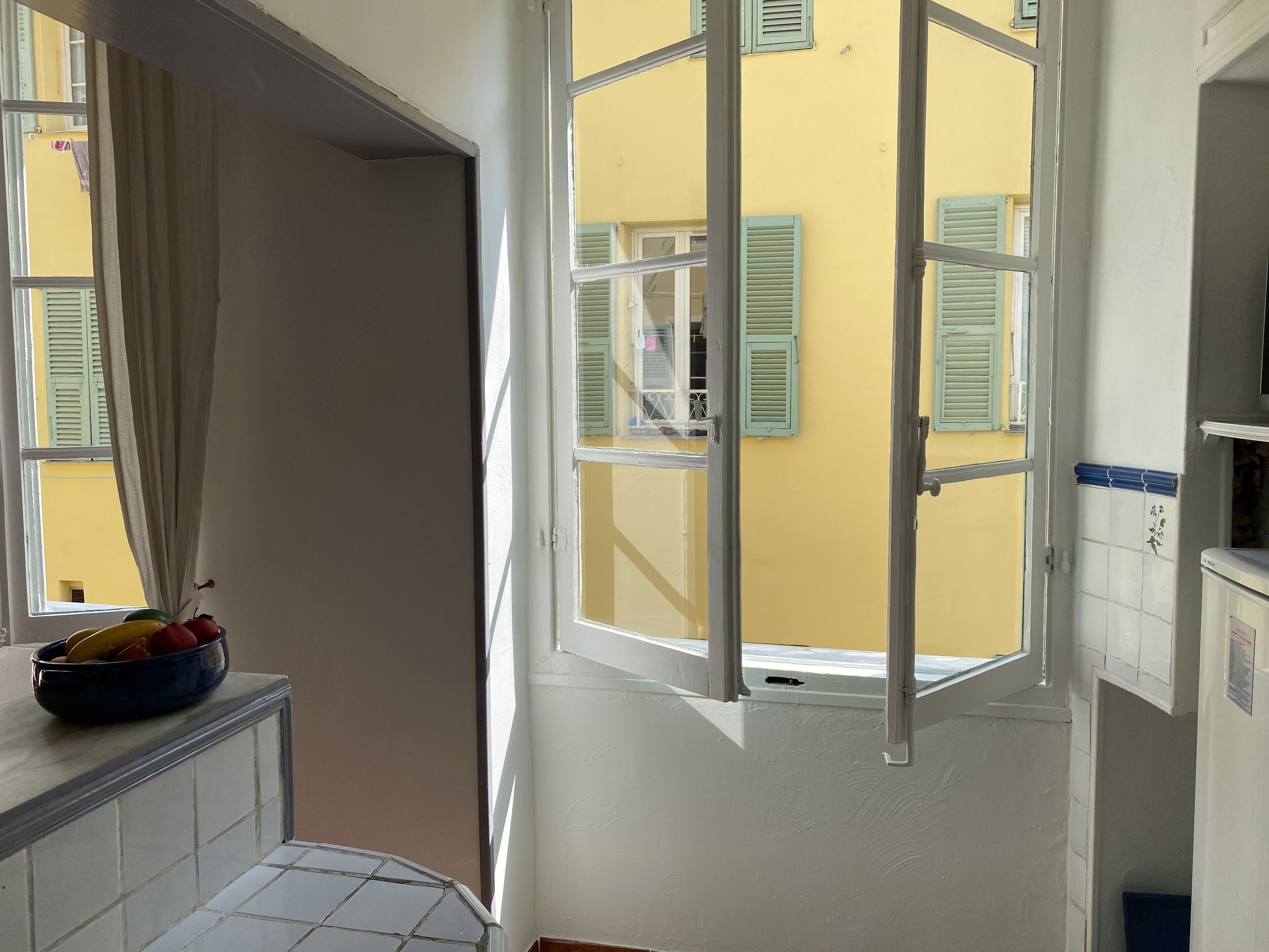 Una cocina con ventana, un frutero y salpicadero de azulejos.