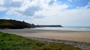 A beach with a rocky shoreline, grassy areas, and a distant view of the sea. - Duplex apartment with large terrace facing the sea (plomodiern)