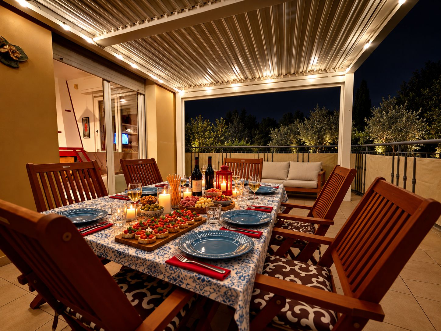An outdoor dining area with a table set for six, surrounded by wooden chairs, under a covered patio with lights.