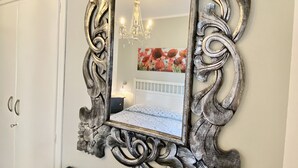 Uno specchio con una cornice decorata, un letto con testiera floreale e un lampadario.