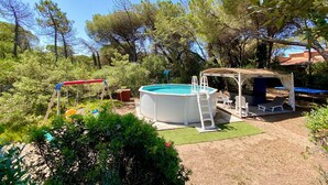 Un giardino sul retro con piscina, un'area salotto coperta e altalene.