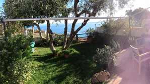 A patio with a view of the sea, surrounded by greenery and potted plants. - Apt with stunning sea view, swimming pool, tennis (Porto Santo Stefano)