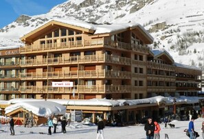 A multi-story wooden building with balconies, ski equipment, and a sign that reads "c'est ici". - Unique Location ! Val d'Isère Snow Front - Ski in Ski Out - Standing (Val-D'isère)