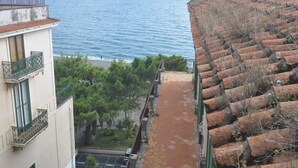 Ein Küstengebäude mit Meerblick, ein Ziegeldach und ein Balkon mit Geländer.