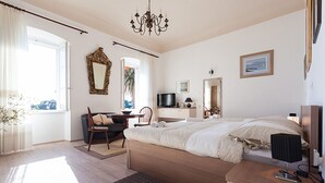 Un dormitorio con cama, escritorio, silla, televisor y espejo.