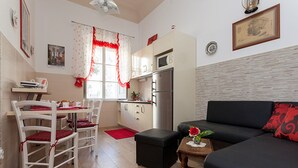 Un espacio habitable compacto con kitchenette, comedor y zona de estar.