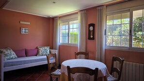 A room with a sofa, a table, chairs, a clock, and windows with curtains. - House Torre del Virrey (L'Eliana)