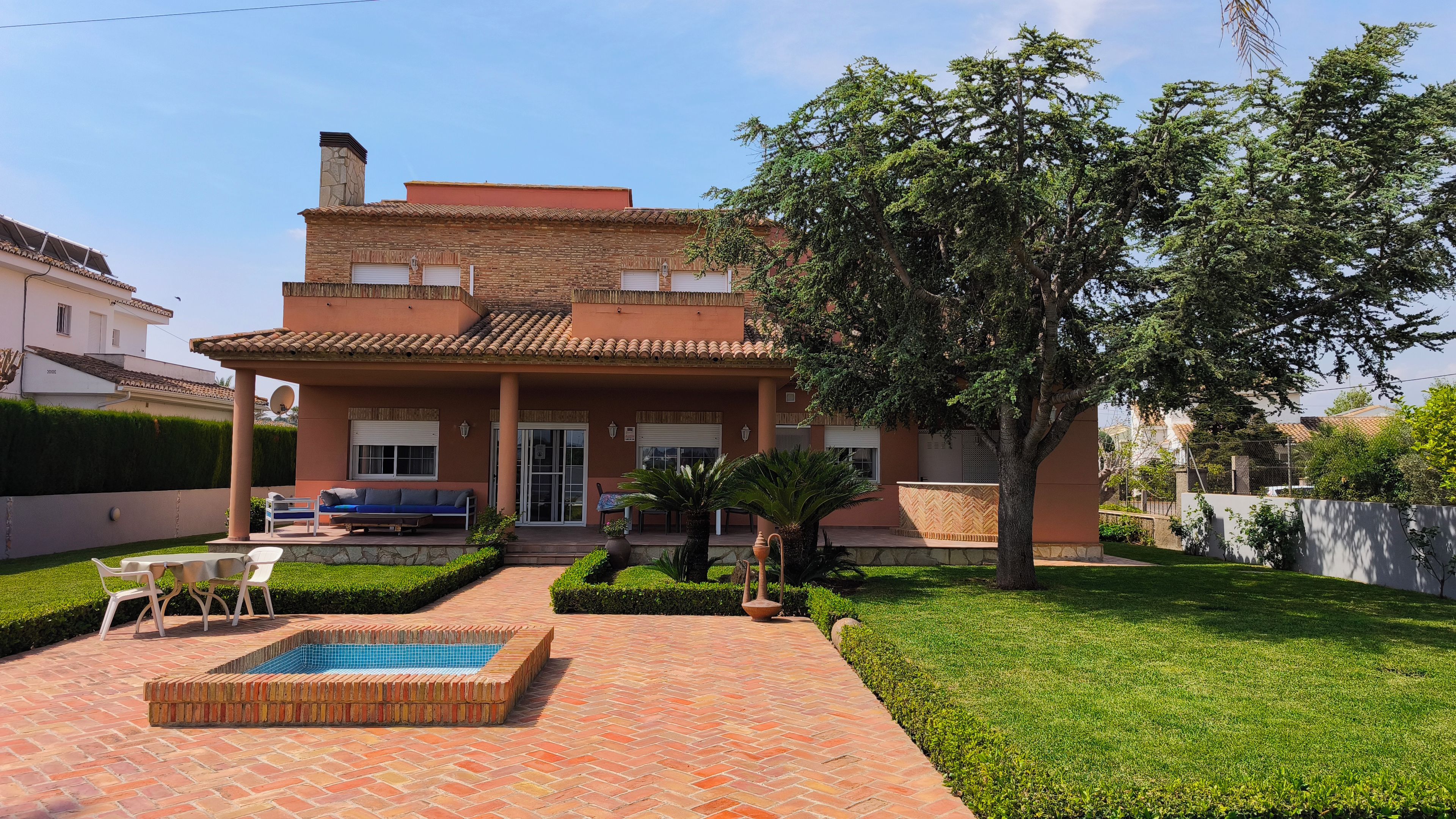Une maison à deux étages avec une piscine, une terrasse et une pelouse bien entretenue.