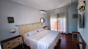 A bedroom with a bed, bedside tables, a mirror, and a window with curtains. - House Torre del Virrey (L'Eliana)