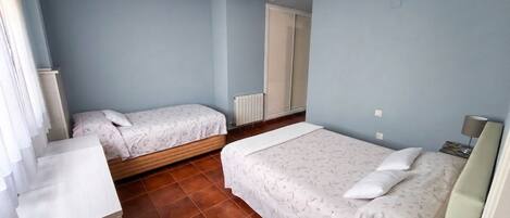 A bedroom with two beds, a radiator, and a window.
