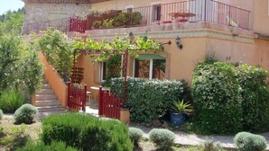 A two-story house with a balcony, a staircase leading to the entrance, and a garden with various plants and a small table. - The calm of the forest, just minutes from the sea (Fréjus)