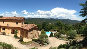 A two-story stone house with a tiled roof, surrounded by lush greenery and a pool. - The calm of the forest, just minutes from the sea (Fréjus)