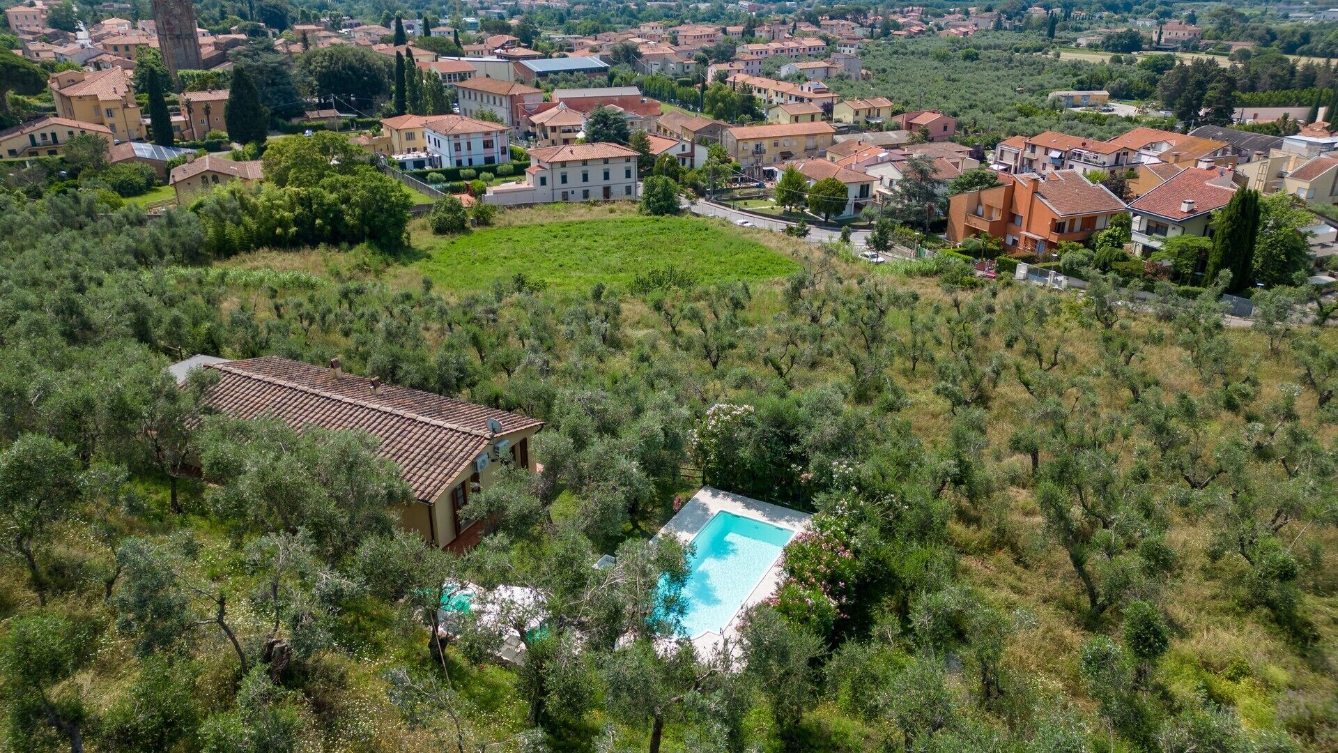 An aerial view of a residential area with houses, a swimming pool, and a garden.