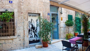 An outdoor seating area with stone walls, a mural, and potted plants. - Clock Tower apartment (Split)