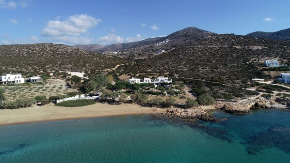 Zona costera con edificios blancos, una playa y montañas al fondo.