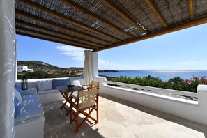 Una terraza con una mesa y sillas, una pared blanca y vistas al mar.