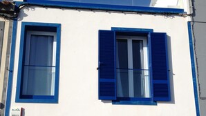 Un bâtiment à deux étages, avec des volets bleus et une façade blanche.