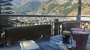 A table with a plate of bread, a container of butter, and jars of jam, set against a mountain backdrop. - Superior apartment with stunning Views of Matterhorn.  1 free return taxi ride (Zermatt)