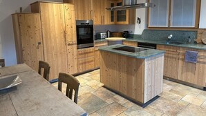 A modern kitchen with wooden cabinets, a built-in oven, a stainless steel range hood, and a granite countertop. - Superior apartment with stunning Views of Matterhorn.  1 free return taxi ride (Zermatt)