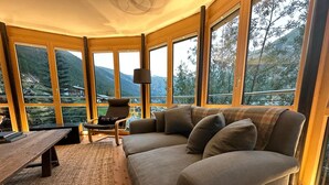 A cozy room with a large window, a sofa, a chair, and a table. - Superior apartment with stunning Views of Matterhorn.  1 free return taxi ride (Zermatt)