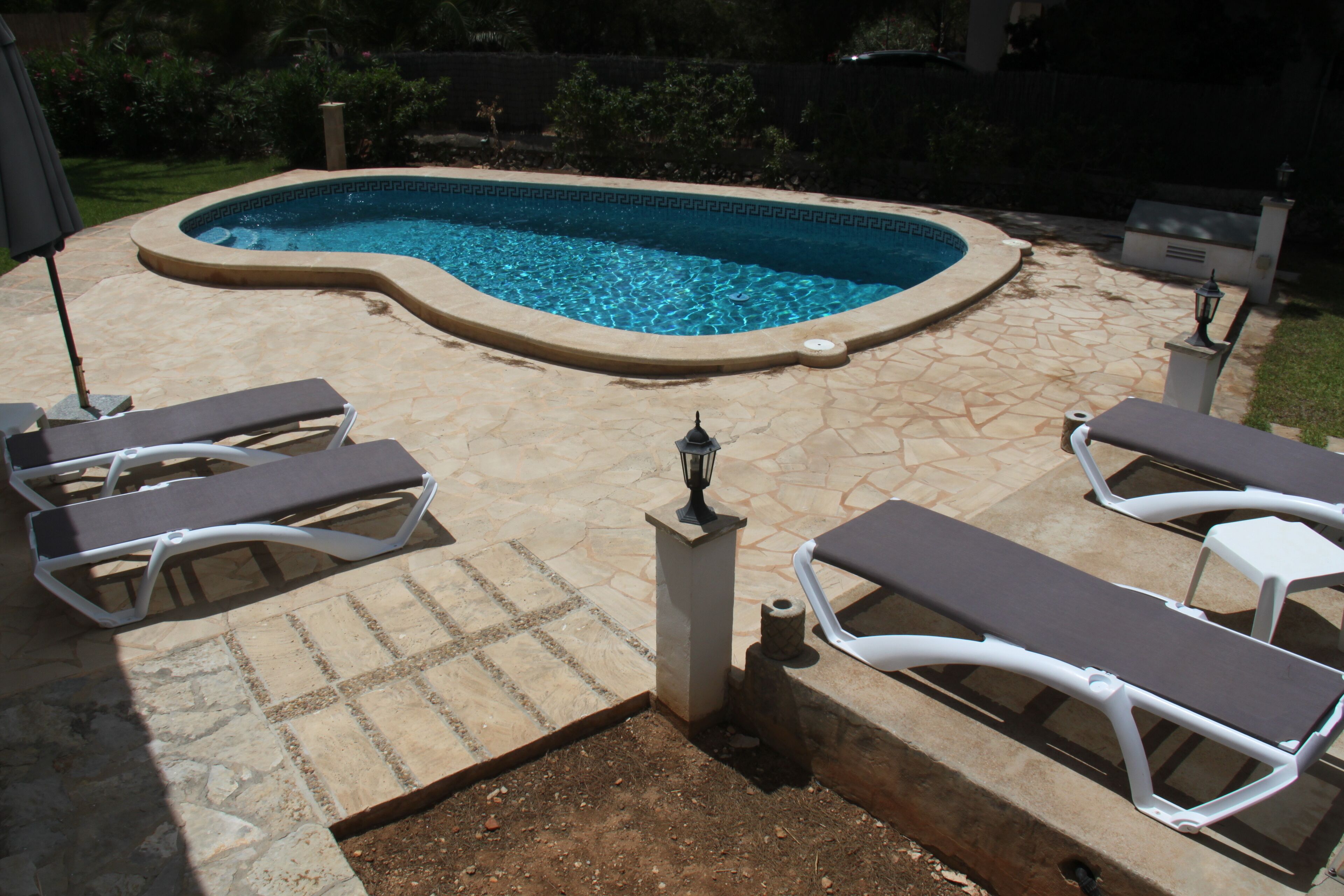 Una piscina amb terrassa de pedra i gandules.