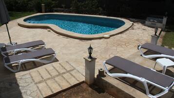 Una piscina amb terrassa de pedra i gandules.