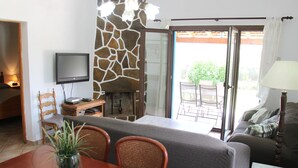 A dining area with a stone wall, a television, and a view of the outdoors. - Villa-Chalet with private pool, POOLSIDE BARBECUE (Manacor)