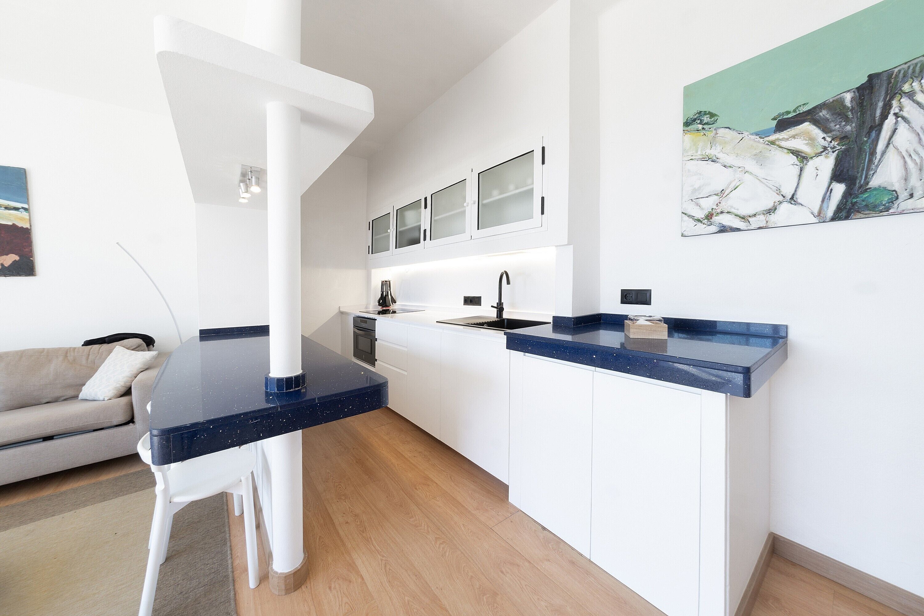 A modern kitchen with white cabinets, a black countertop, and a built-in oven.