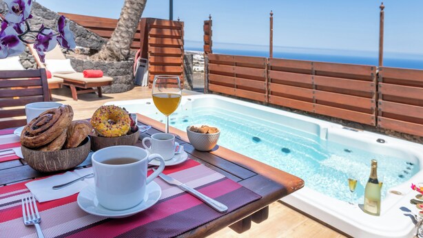 Ontbijt bij het zwembad met een jacuzzi, met croissants, een donut en een glas sinaasappelsap.