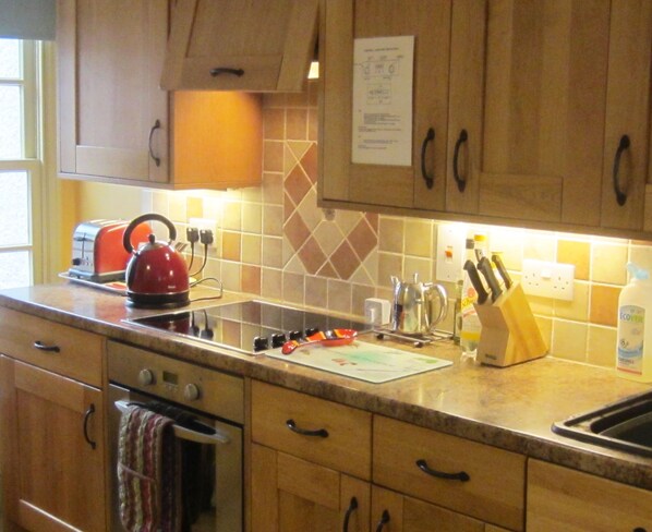 A kitchen with wooden cabinets, a stainless steel sink, a kettle, a toaster, and a knife block.