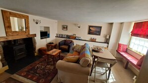 Una sala de estar acogedora con chimenea, sofá, mesa de centro y televisor.