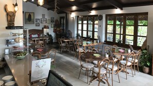 Un restaurante con mesas y sillas de madera, un atril para el menú y lámparas colgantes.