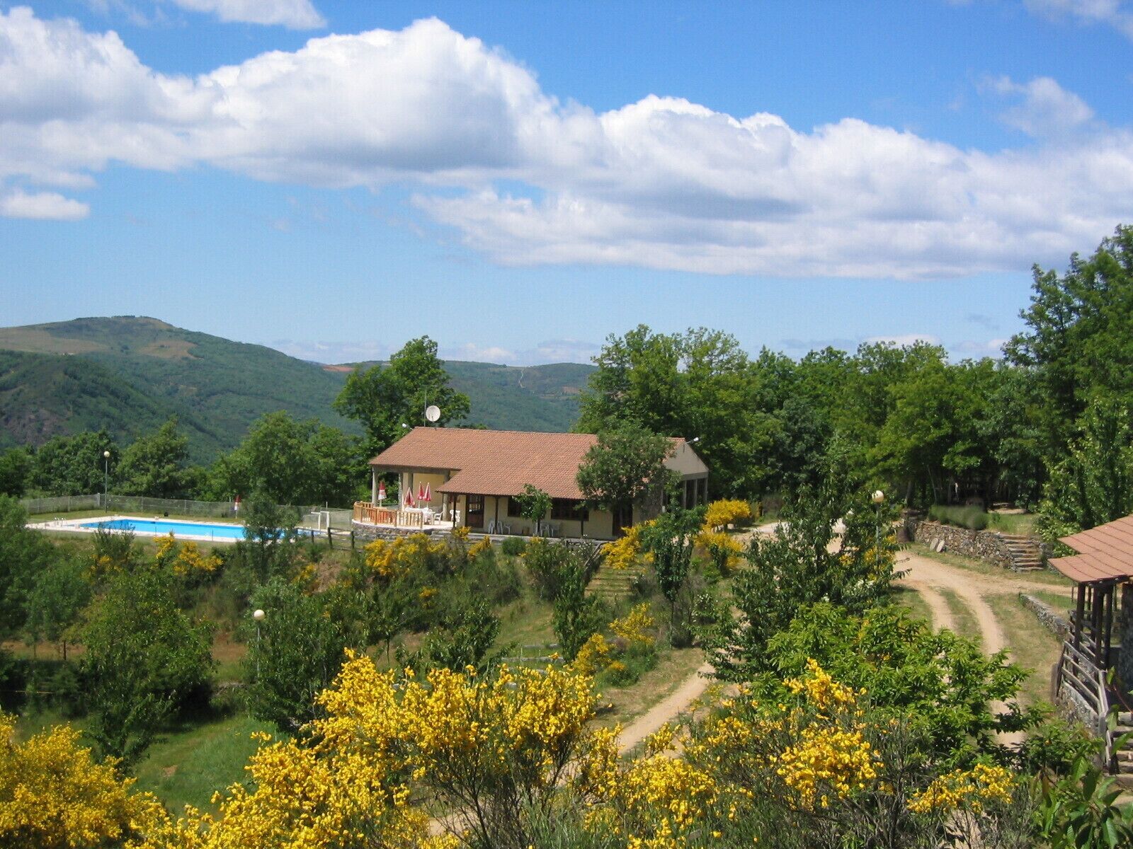 A house with a swimming pool, surrounded by lush greenery and hills.