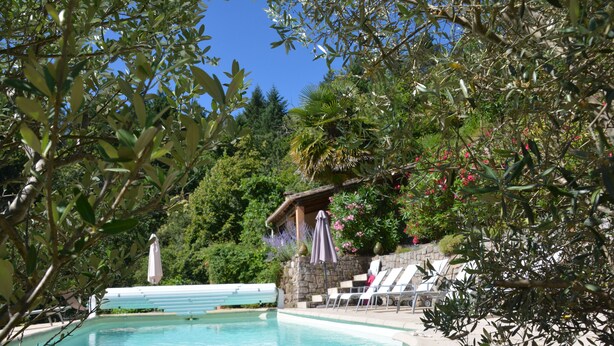 A swimming pool with lounge chairs and umbrellas, surrounded by greenery and a stone wall. - House with character in the Countryside/mountain - 6 bedrooms - Cevennes/Gard (Soudorgues)