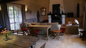 A cozy living room with a wooden dining table, a sofa, and a fireplace. - House with character in the Countryside/mountain - 6 bedrooms - Cevennes/Gard (Soudorgues)