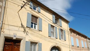 Un bâtiment à deux étages avec une façade beige, une porte en bois et des volets bleus.