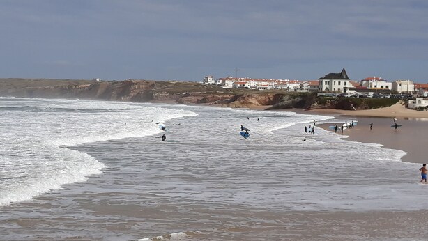 A beach with waves, people, and buildings in the background. - Small and lovelly villa, in the center of Peniche, in a quiet zone, for 5 persons (Peniche)