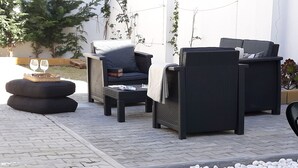 An outdoor seating area with wicker furniture, a small table with two glasses, and a pebbled ground. - Small and lovelly villa, in the center of Peniche, in a quiet zone, for 5 persons (Peniche)