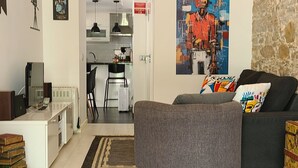 A modern living room with a grey sofa, a coffee table, a TV, and a painting on the wall. - Small and lovelly villa, in the center of Peniche, in a quiet zone, for 5 persons (Peniche)
