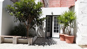 A courtyard with potted plants, a concrete bench, and a door leading to a building. - Small and lovelly villa, in the center of Peniche, in a quiet zone, for 5 persons (Peniche)