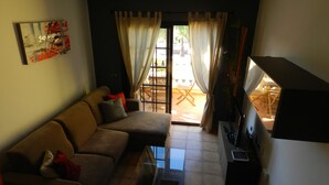 A living room with a sofa, a glass coffee table, and a TV stand. - Wonderful apartment in Bahía del Duque - Pool, 2 Terraces, Wifi ... (Costa Adeje)