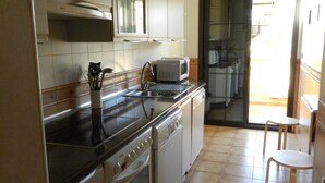 A kitchen with white cabinets, a stove, a microwave, and a sink. - Wonderful apartment in Bahía del Duque - Pool, 2 Terraces, Wifi ... (Costa Adeje)