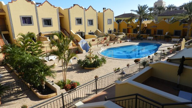 A pool area with a fountain, surrounded by palm trees and lounge chairs. - Wonderful apartment in Bahía del Duque - Pool, 2 Terraces, Wifi ... (Costa Adeje)