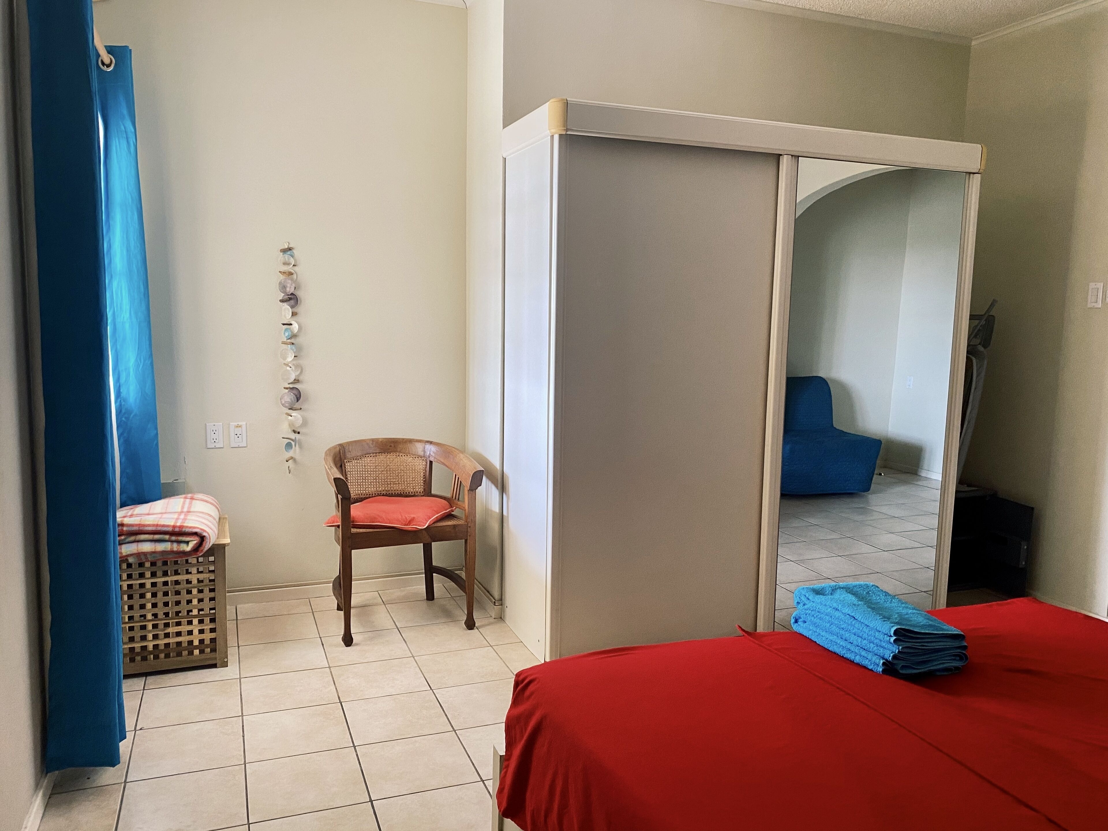 A hotel room with a bed, a chair, a wardrobe, and a laundry basket.