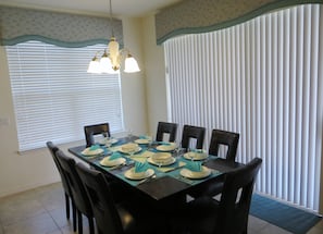 A dining room with a rectangular table set for four, surrounded by black chairs. - Beautiful Spacious Gated Modern Luxury Villa Overlooking Conservation Area 7BD6B (Davenport)