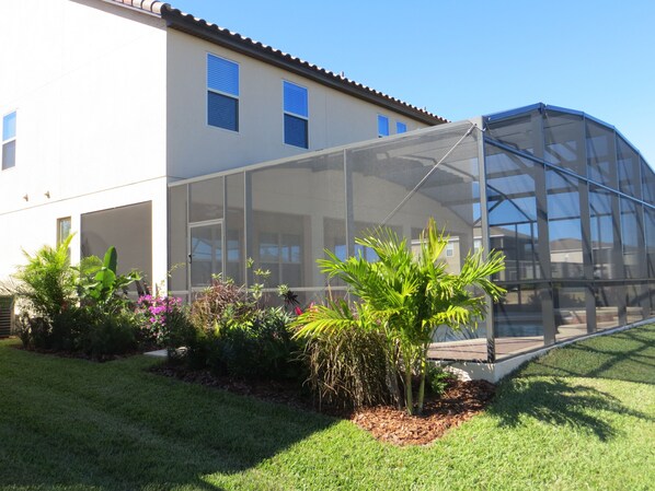 A house with a large glass-enclosed porch, surrounded by a well-maintained garden with various plants and flowers. - Beautiful Spacious Gated Modern Luxury Villa Overlooking Conservation Area 7BD6B (Davenport)