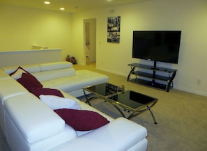 A living room with a white sofa, a glass coffee table, and a flat-screen TV on a stand. - Beautiful Spacious Gated Modern Luxury Villa Overlooking Conservation Area 7BD6B (Davenport)