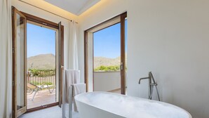 A modern bathroom with a freestanding bathtub, large windows, and a view of a mountainous landscape. - Villa Can Dala luxury in Port de Pollensa Sleeps 12 (Puerto Pollensa)